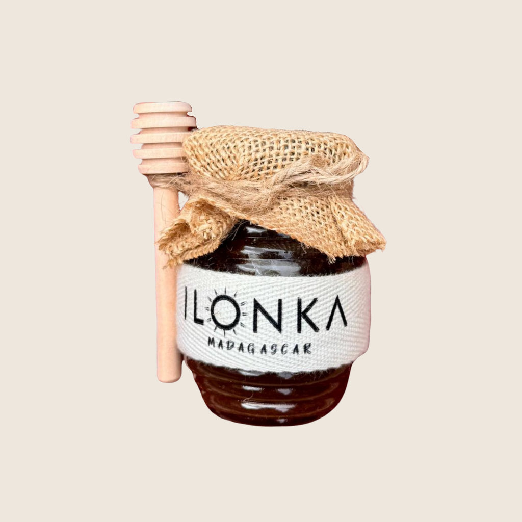 Eucalyptus Honey from Madagascar | Ilonka – honey jar with jute cover and wooden dipper on beige background