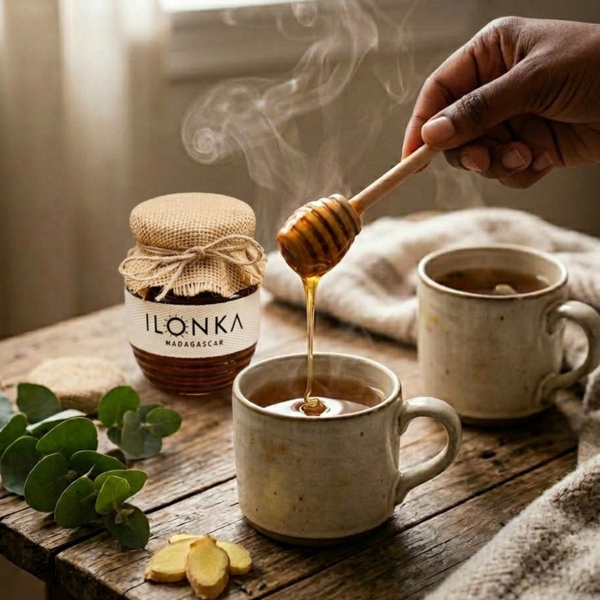 Eucalyptus Honey from Madagascar | Ilonka – wooden dipper drizzling honey into a cup of tea with eucalyptus leaves